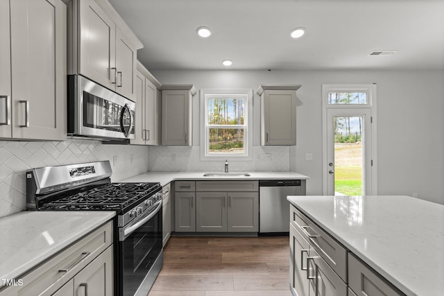 110 Merrifield Ln, Garner, NC 27529 - kitchen with appliances with stainless steel finishes, a sink, gray cabinetry, dark wood finished floors, and backsplash