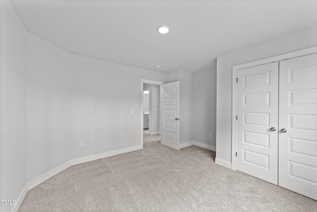 unfurnished bedroom featuring light colored carpet and a closet