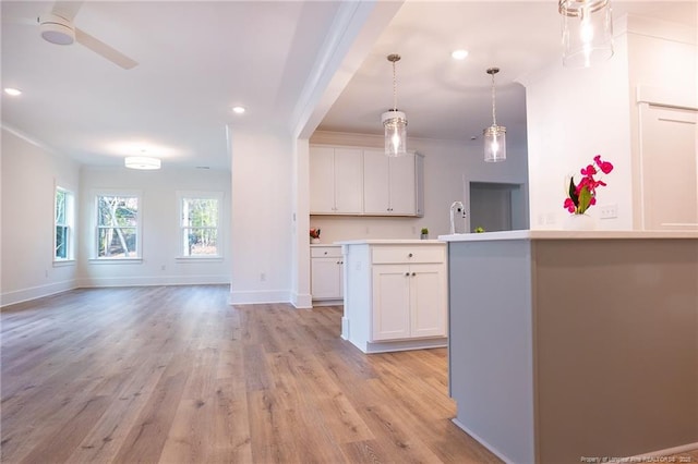 kitchen featuring white cabinetry, light hardwood / wood-style floors, a kitchen island with sink, and pendant lighting