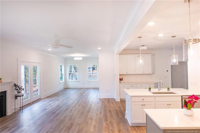 kitchen with a kitchen island with sink, sink, decorative light fixtures, and white cabinets