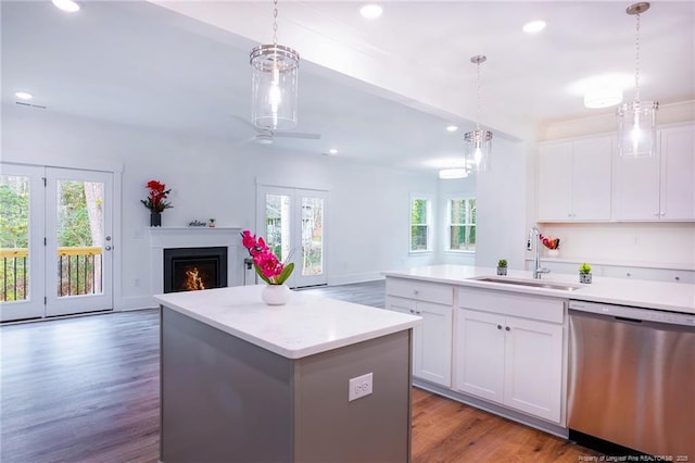 kitchen featuring white cabinetry, stainless steel dishwasher, decorative light fixtures, and sink