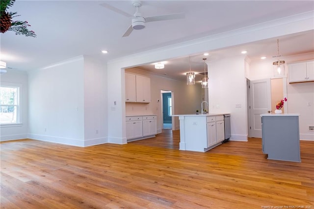 kitchen featuring hanging light fixtures, white cabinetry, sink, and light hardwood / wood-style floors