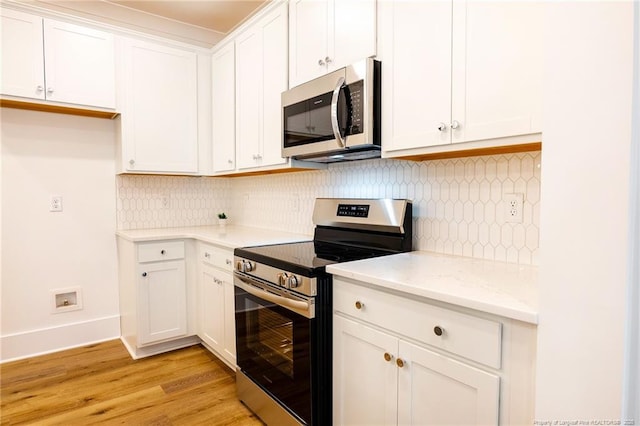 kitchen featuring white cabinetry, light stone countertops, light hardwood / wood-style floors, and appliances with stainless steel finishes