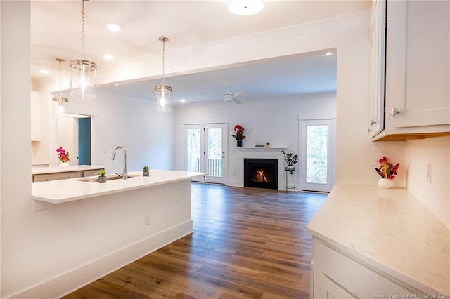 kitchen with dark hardwood / wood-style floors, decorative light fixtures, sink, white cabinets, and plenty of natural light