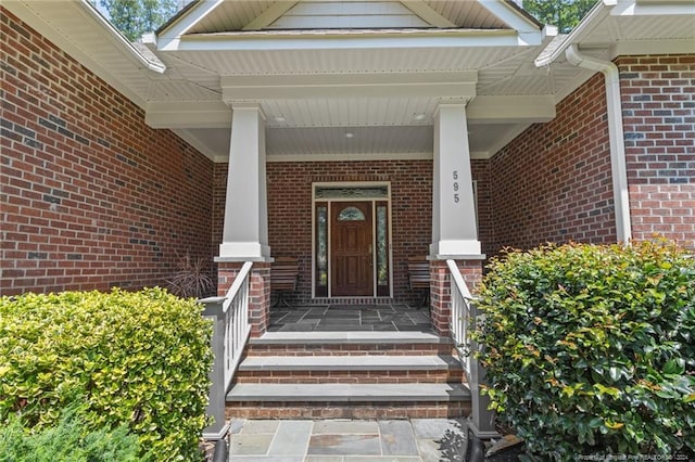 property entrance with brick siding and a porch
