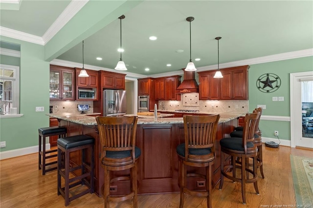 kitchen with ornamental molding, stainless steel appliances, light wood-style floors, baseboards, and custom exhaust hood
