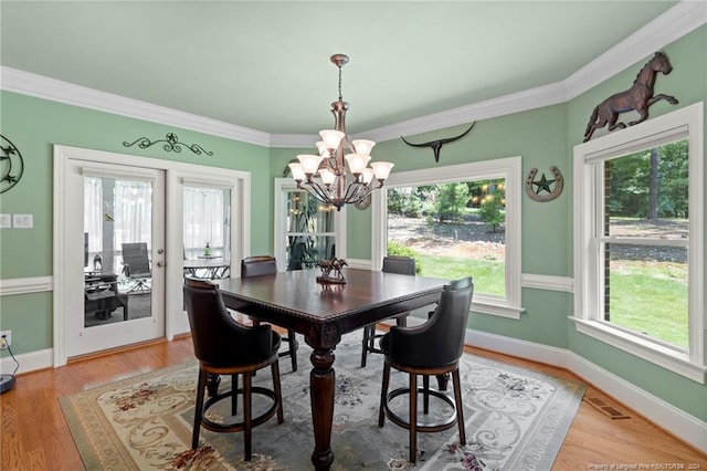 dining area with visible vents, a chandelier, crown molding, and light wood-style flooring