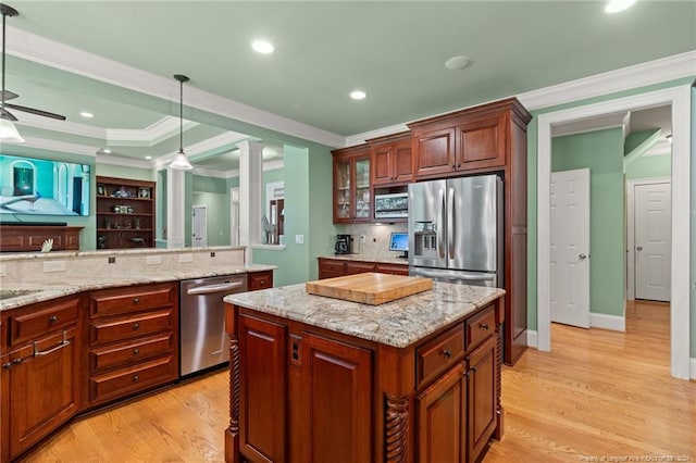 kitchen featuring decorative light fixtures, stainless steel appliances, ornamental molding, and light wood finished floors