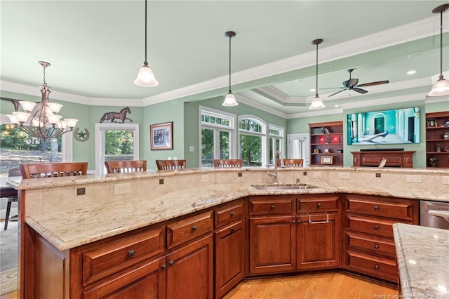 kitchen featuring brown cabinetry, crown molding, ceiling fan with notable chandelier, and a sink