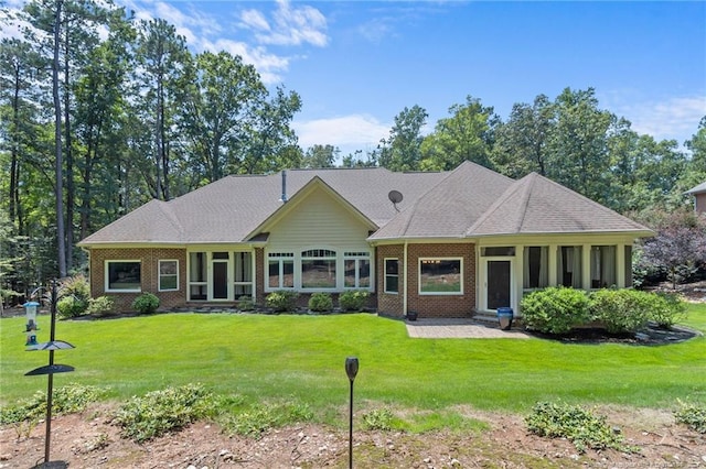 view of front of house with brick siding, a front lawn, and a sunroom