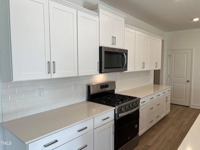 kitchen with decorative backsplash, stainless steel appliances, white cabinetry, and dark hardwood / wood-style floors