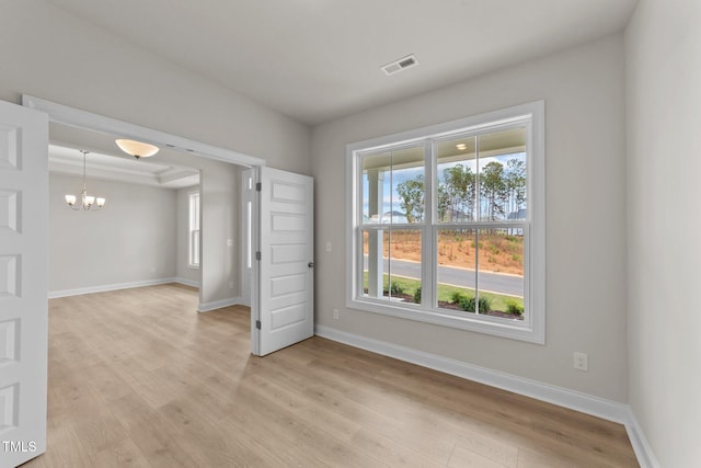 unfurnished room featuring a chandelier and light hardwood / wood-style flooring