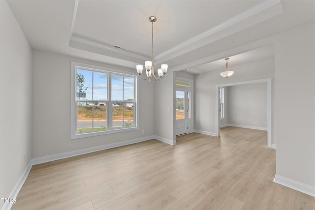 unfurnished room featuring light wood-type flooring, a tray ceiling, a notable chandelier, and a healthy amount of sunlight