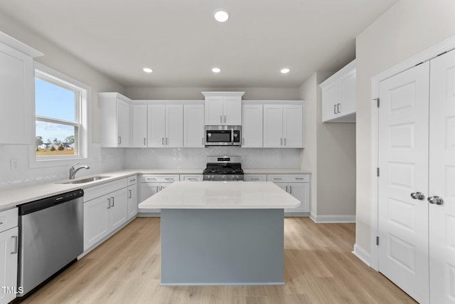 kitchen featuring stainless steel appliances, white cabinetry, light wood-type flooring, and a center island