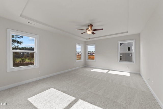 carpeted empty room featuring ceiling fan and a raised ceiling