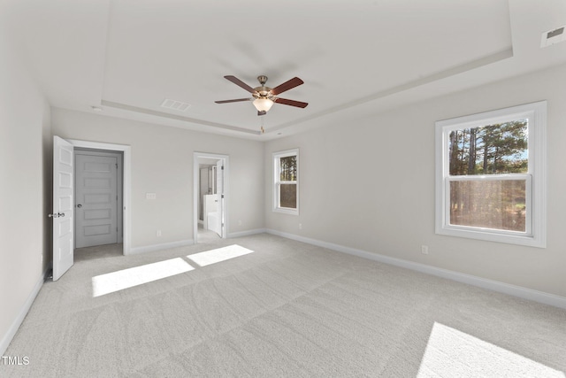 carpeted empty room featuring ceiling fan and a tray ceiling