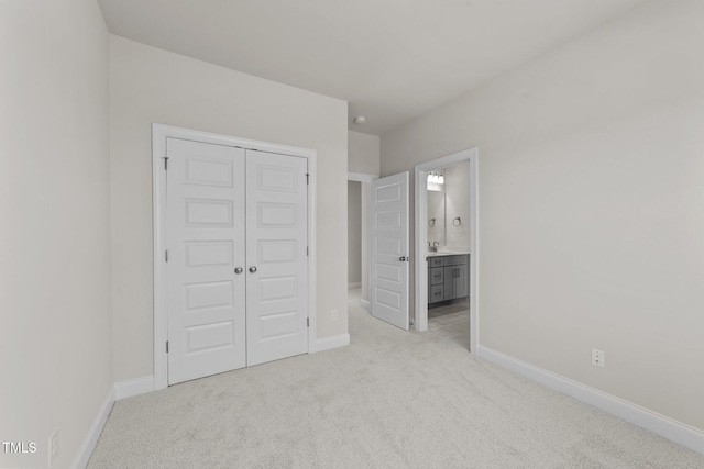 unfurnished bedroom featuring light colored carpet, ensuite bath, and a closet