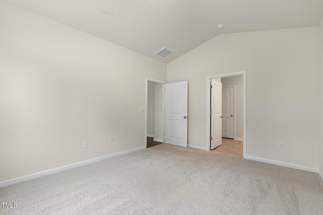 unfurnished bedroom with vaulted ceiling and light carpet