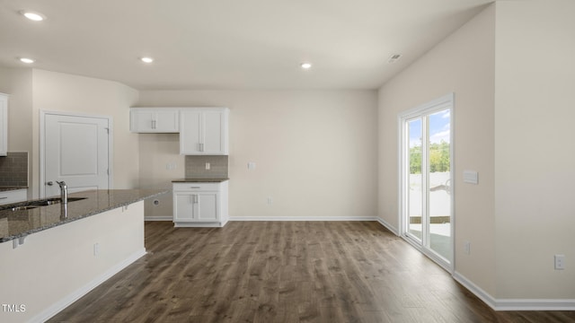 kitchen featuring sink, white cabinetry, backsplash, dark hardwood / wood-style floors, and dark stone counters