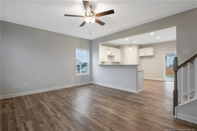 unfurnished living room featuring ceiling fan and dark hardwood / wood-style floors