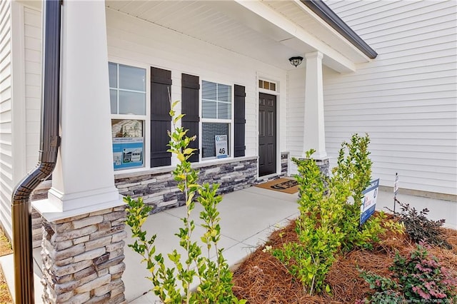  - view of exterior entry with covered porch and stone siding