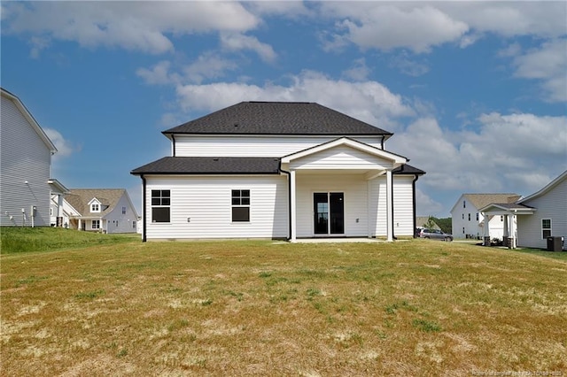  - back of property with a yard, central air condition unit, and a shingled roof