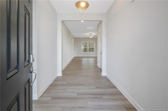 hallway featuring light wood-type flooring, visible vents, and baseboards