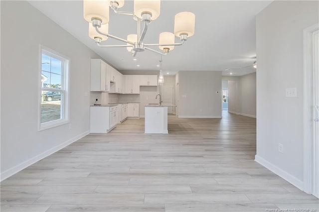 kitchen with a notable chandelier, hanging light fixtures, open floor plan, white cabinetry, and a kitchen island