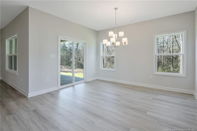 unfurnished dining area featuring light wood finished floors, baseboards, and an inviting chandelier