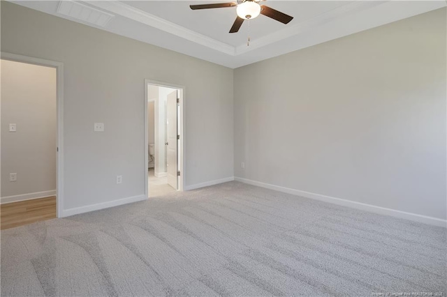 unfurnished room featuring ceiling fan, light colored carpet, visible vents, baseboards, and a raised ceiling