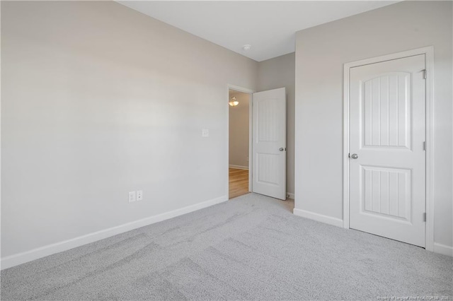 unfurnished bedroom featuring light carpet and baseboards