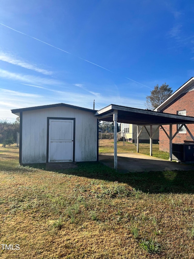 view of outbuilding with a carport, central AC, and a yard