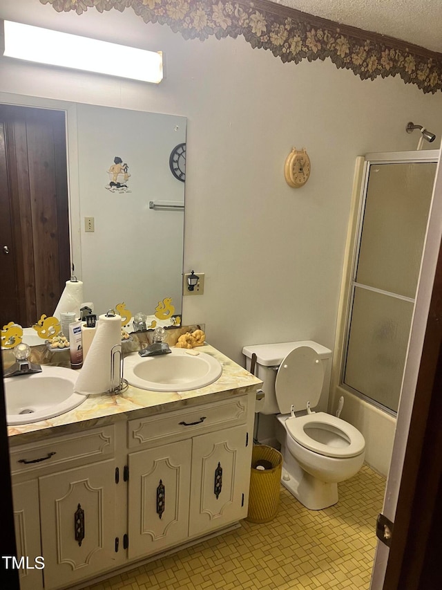 full bathroom with tile patterned floors, double sink vanity, enclosed tub / shower combo, toilet, and a textured ceiling