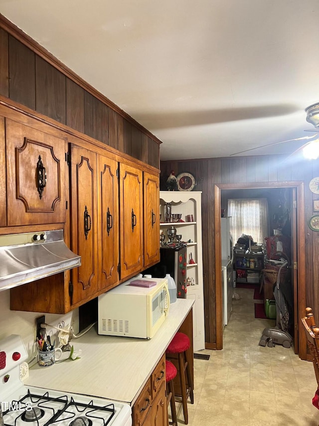 kitchen featuring stainless steel fridge, range, light tile patterned floors, and wooden walls