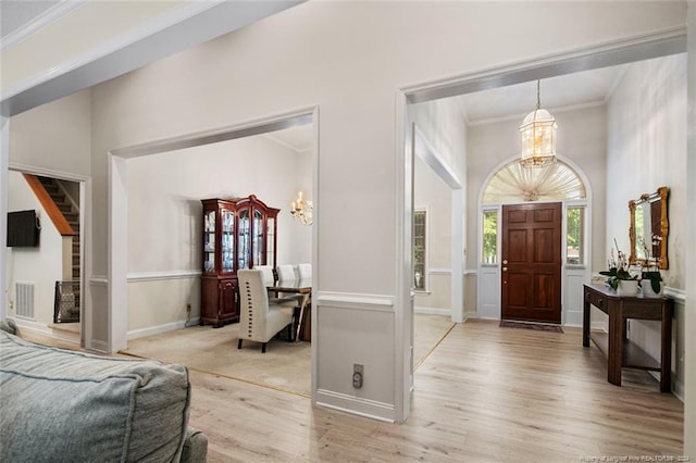 foyer with light hardwood / wood-style floors, an inviting chandelier, and crown molding