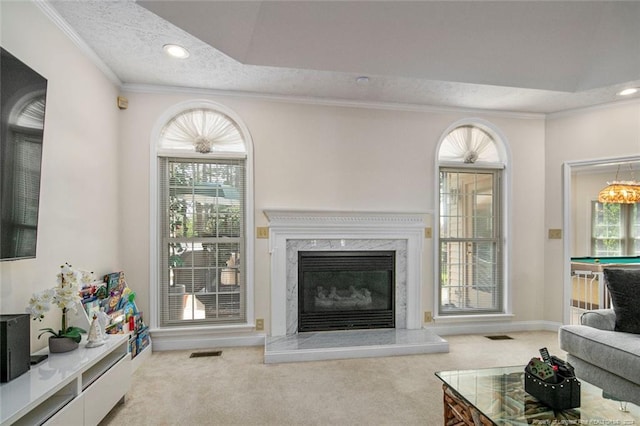 carpeted living room with a fireplace, ornamental molding, a textured ceiling, and a healthy amount of sunlight