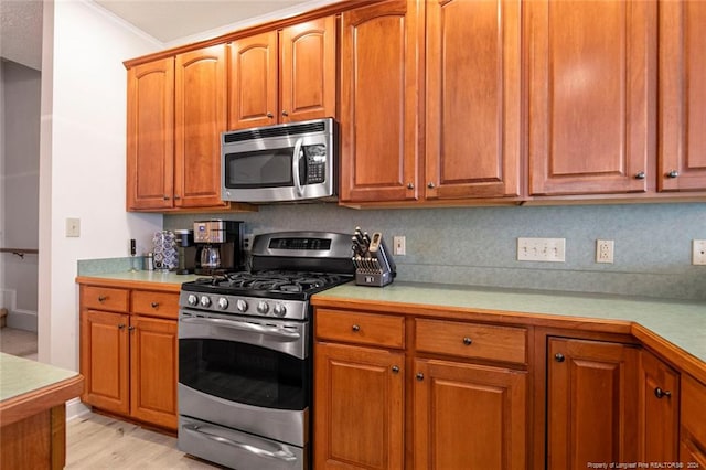 kitchen with decorative backsplash, light hardwood / wood-style flooring, stainless steel appliances, and ornamental molding