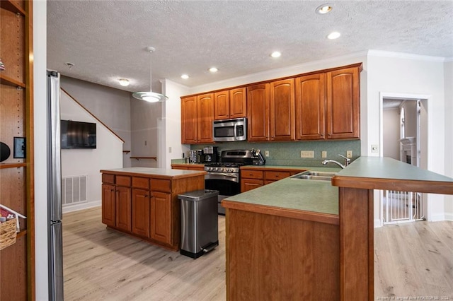 kitchen with light hardwood / wood-style floors, kitchen peninsula, sink, and appliances with stainless steel finishes