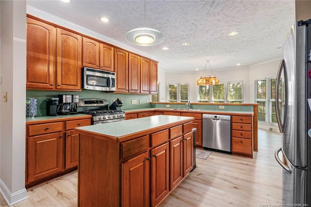 kitchen featuring stainless steel appliances, sink, light hardwood / wood-style floors, a kitchen island, and hanging light fixtures