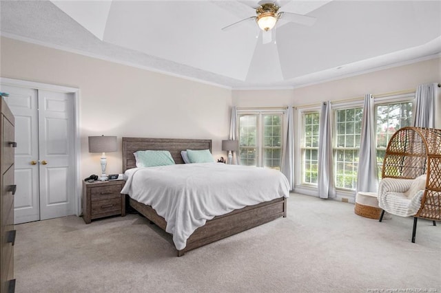 bedroom with a raised ceiling, ceiling fan, light colored carpet, and crown molding