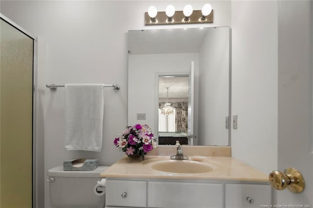 bathroom featuring vanity, toilet, and a chandelier