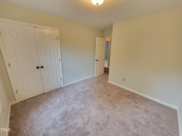 unfurnished bedroom with light colored carpet and a closet