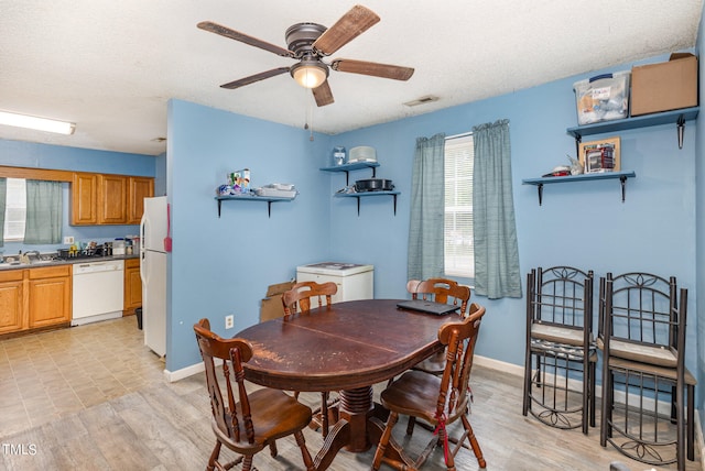 dining room featuring a textured ceiling, light hardwood / wood-style flooring, sink, and ceiling fan