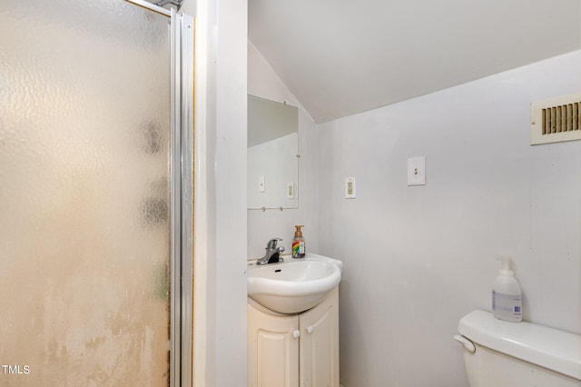 bathroom with a shower with shower door, vanity, toilet, and vaulted ceiling