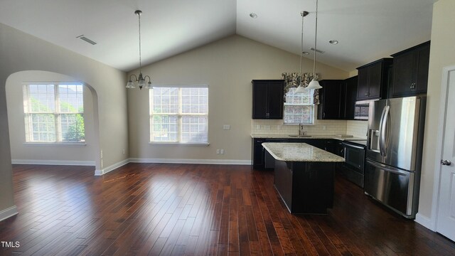 kitchen with a sink, stainless steel appliances, a center island, light stone countertops, and vaulted ceiling