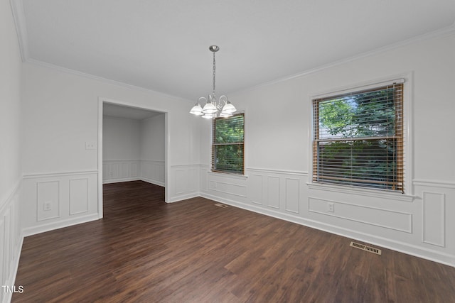 spare room featuring crown molding, dark wood-type flooring, and a chandelier