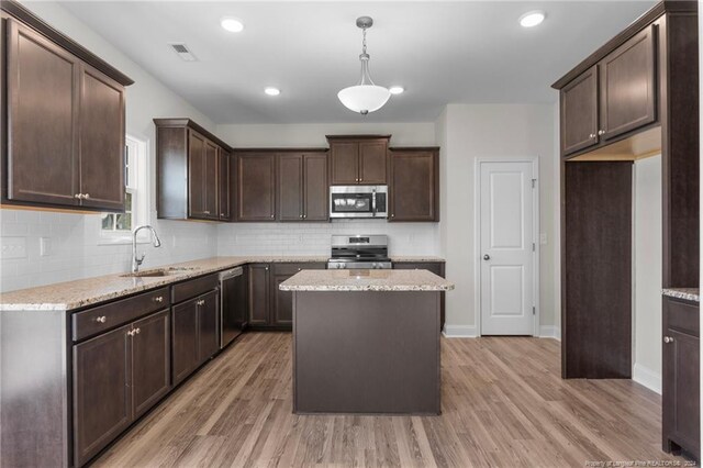 kitchen with wood-type flooring, appliances with stainless steel finishes, a center island, and sink