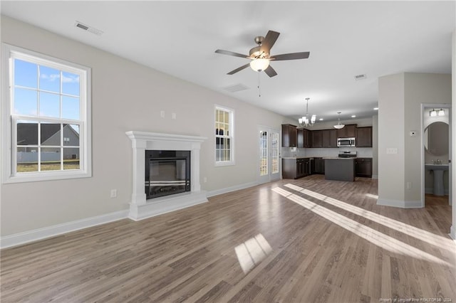 unfurnished living room featuring hardwood / wood-style floors and ceiling fan with notable chandelier