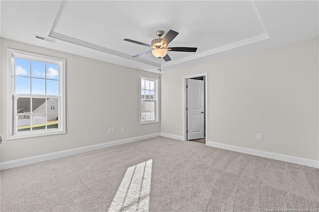 unfurnished room featuring carpet flooring, ceiling fan, ornamental molding, and a tray ceiling