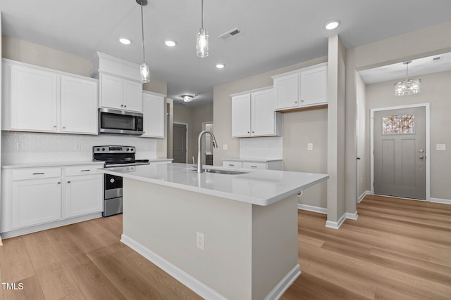 kitchen featuring sink, white cabinetry, appliances with stainless steel finishes, and an island with sink